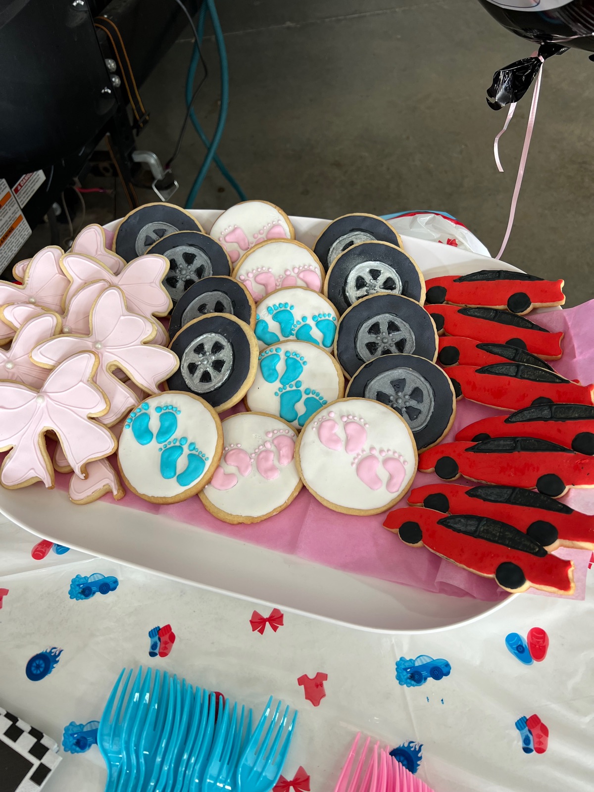 Platter of decorated cookies: bows, tires, baby feet and race cars