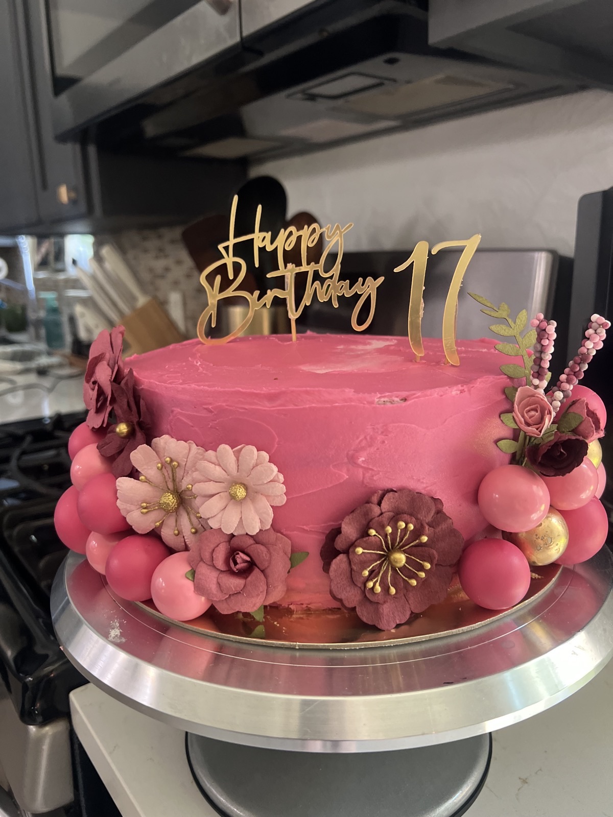 Pink buttercream birthday cake with sugar flowers, pink pearls and a gold Happy Birthday 17 topper
