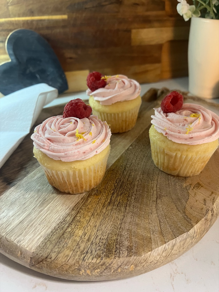 Vanilla cupcakes with pink raspberry swirl frosting, fresh raspberries and citrus zest